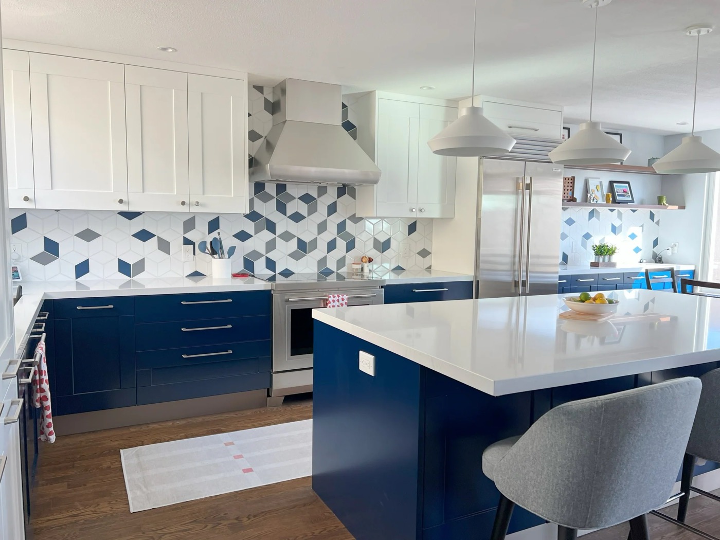 A completed kitchen remodel by Build For Life Construction. Navy cabinets, tile backsplash, quartz island.